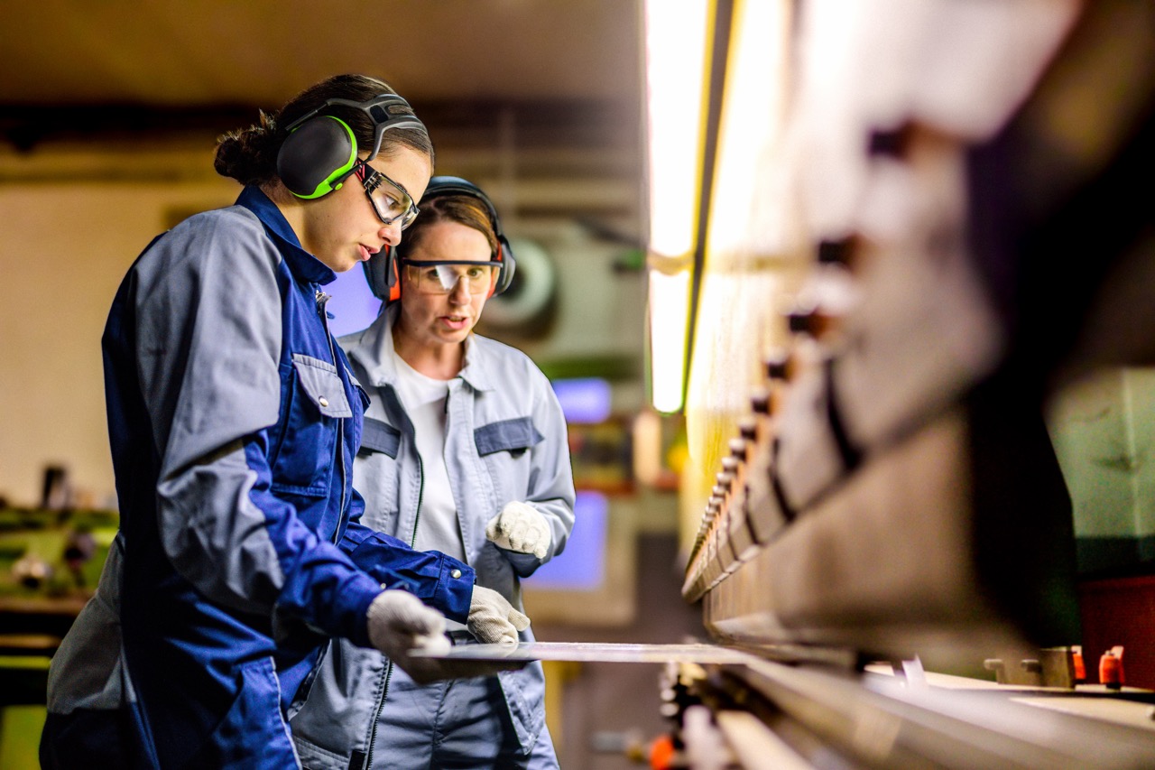 Skilled Female Workers Operating Press Brake in Industrial Setting